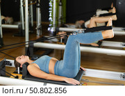Girl lying on foldable bed reformer performs exercises, strengthening body and muscles. Стоковое фото, фотограф Яков Филимонов / Фотобанк Лори