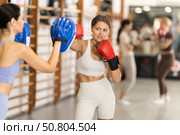Woman works out strength and speed of boxing punch mitts with help of partner in boxing paws. Стоковое фото, фотограф Яков Филимонов / Фотобанк Лори