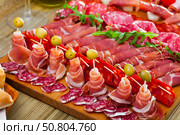 Slicing sausages fuet, ham, salami, chorizo with cherry tomatoes and olives. Стоковое фото, фотограф Яков Филимонов / Фотобанк Лори