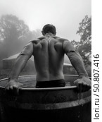Strong man emerging from an icy outdoor tub surrounded by fog, showcasing cold therapy, masculine strength, and wellness recovery in natural conditions. Стоковое AI-изображение, AI-художник Александра Троицкая / Фотобанк Лори