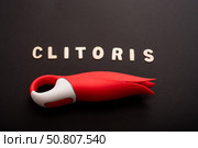 An overhead view of a red tulip shaped clitoral vibrator and the inscription clitoris on a black background. Стоковое фото, фотограф Михаил Решетников / Фотобанк Лори