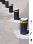 Дорожный блокиратор в виде выдвижных металлических столбов. The barrier is automatic in a parking lot in a modern city. Стоковое фото, фотограф Татьяна Д / Фотобанк Лори