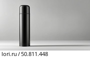 Stylish black thermos for hot beverages on a gray background. Стоковое AI-изображение, AI-художник Katsiaryna Repich / Фотобанк Лори