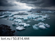 Ice floes floating in the ocean are the remnants of a melting glacier against the background of dark thunderclouds. Стоковое AI-изображение, AI-художник Алексей Кузнецов / Фотобанк Лори