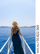 Tekirova, Turkey - June 14, 2025: woman stands on the bow of a yacht and looks into the distance. Стоковое фото, фотограф Анастасия Мерчик / Фотобанк Лори