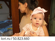 Молодая мама держит пятимесячную девочку на руках в старинном деревянном коридоре. Стоковое фото, фотограф Владислав Войтов / Фотобанк Лори