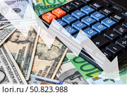 Down arrow on the background of dollar and euro bills and calculator. The concept of inflation, depreciation of the currency or the economy of the country. Стоковое фото, фотограф Емельянов Евгений Викторович / Фотобанк Лори