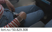 Close-up of female passenger hands unfastening airplane seat belt and relaxing after landing, wearing casual striped shirt and jeans, sitting in aircraft seat, aviation travel safety. Стоковое видео, видеограф Сергей Тимофеев / Фотобанк Лори