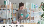Female shopper chooses best mouthwash in supermarket. Стоковое видео, видеограф Яков Филимонов / Фотобанк Лори