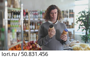 Male buyer choosing cans of beans in supermarket. Стоковое видео, видеограф Яков Филимонов / Фотобанк Лори