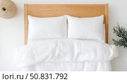 Cozy bedroom setup with white linens and wooden headboard for relaxation. Стоковое AI-изображение, AI-художник Katsiaryna Repich / Фотобанк Лори