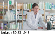 Focused young female pharmacy worker in white coat using desktop computer to update product quantities and manage inventory during routine stock control. Стоковое видео, видеограф Яков Филимонов / Фотобанк Лори