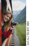 Beautiful happy young woman hangs out of train open window and make photo on vintage analog camera. Travel and explore more wanderlust concept. Female touristing mountains. Стоковое AI-видео, аниматор Sergey Grishin / Фотобанк Лори