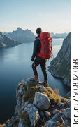 Amazing epic shot of young man hiker stand on top of mountain after long difficult hike in Lofoten Islands in Norway. Incredible summer views of scandinavian travel lifestyle. Epic. Стоковое AI-видео, аниматор Sergey Grishin / Фотобанк Лори