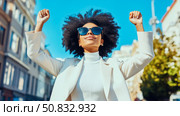 Triumphant Woman with Afro Hairstyle Celebrating Success in the City. Стоковое AI-изображение, AI-художник Данила Большаков / Фотобанк Лори