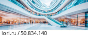 Futuristic Atrium: Shoppers in a modern circular mall, complete with sweeping curves, an escalator, and a light, airy ambiance. Стоковое AI-изображение, AI-художник Данила Большаков / Фотобанк Лори