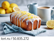 Homemade lemon drizzle cake with icing. Classic lemon pound cake with citrus glaze and zest. Whole loaf, side view, close up. Fresh homemade baked dessert with lemon slices. Blurred tea set background. Стоковое AI-изображение, AI-художник Марина Демидюк / Фотобанк Лори