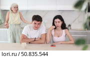 Elderly mom make claims to young couple in home kitchen. Стоковое видео, видеограф Яков Филимонов / Фотобанк Лори