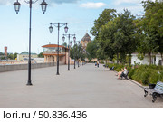 Yevpatoria, Russian Federation - July 05, 2025: Scenic waterfront promenade with benches and lampposts, featuring lush greenery and historic architecture in the background, ideal for leisurely strolls. Редакционное фото, фотограф Ирина Ручушкина / Фотобанк Лори