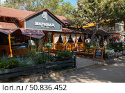 Yevpatoria, Russian Federation - July 05, 2025: Restaurant Marinal, established in 1998, features outdoor seating and vibrant greenery, inviting guests to enjoy a meal in a charming atmosphere. Редакционное фото, фотограф Ирина Ручушкина / Фотобанк Лори