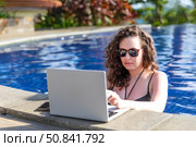 Young freelancer traveler woman working remotely on computer at pool in luxury resort during her summer holiday. Work from anywhere, Technology and lifestyle concept, copy space. High quality photo. Стоковое фото, фотограф Ирина Михайличенко / Фотобанк Лори