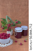 Vertical video of ripe freshly picked raspberries in bowl, jars of homemade jam and bouquet of raspberry branches with berries on wooden garden tableon on summer day. Harvesting organic  berries. Стоковое видео, видеограф Виктория Катьянова / Фотобанк Лори