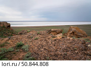 Fancy stones on the slopes of Bolshoe Bogdo Mountain and the salt lake Baskunchak in the distance on a summer day, Bogdinsko-Baskunchak Nature Reserve, Akhtubinsky district, Astrakhan region, Russia. Стоковое фото, фотограф Ula Ulachka / Фотобанк Лори