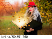 A beautiful woman with a book of magic spells with falling autumn leaves is conjuring. Стоковое фото, фотограф Лазаренко Светлана / Фотобанк Лори