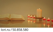 Open Holy Bible book on marble table with seven lit votive candles in church. Стоковое видео, видеограф Igor Tichonow / Фотобанк Лори