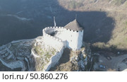 A mesmerizing drone flight around a petite medieval castle majestically perched on a mountain summit. This cinematic aerial showcase reveals the fortress's ancient stonework and commanding views. Стоковое видео, видеограф Виктор Ветошкин / Фотобанк Лори