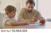 Dad teaches his son writing and counting. Kids primary education. Children learn, study in home school. Daddy male helping teaching little child boy support studying, learning homework. Knowledge day. Стоковое видео, видеограф Марина Демидюк / Фотобанк Лори