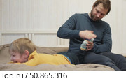 Father using a spiky massage ball for son to relieve muscle tension, aid recovery after intense training. Dad massaging a child boy with tactile knobby ball. Kid rolling sensory ball. Therapy muscles. Стоковое видео, видеограф Марина Демидюк / Фотобанк Лори