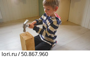 Kid hammers nails to wood with a hammer. Little boy helping with toy tools. Funny 6 years child having fun on building. Kid hammering crafting stuff using wooden pieces. Carpentry and family concept. Стоковое видео, видеограф Марина Демидюк / Фотобанк Лори