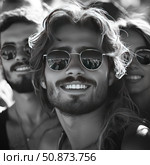 A black and white photograph of a group of young people enjoying the moment. In the center of the frame is a smiling man with thick hair and a beard, wearing sunglasses that reflect the bright scene. His friends, also wearing glasses and with slight smiles, create an atmosphere of friendship, energy and joy. The photo conveys a sense of freedom, summer vacation and youth. Suitable for themes related to lifestyle, fashion, youth and emotions. Стоковое AI-изображение, AI-художник Анна Кривицкая / Фотобанк Лори