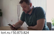 Man using his cellphone. Handsome guy use mobile phone at home. Male browses social networks, gaming, does shopping online, chats with friends, writes or reads messages. Close up. 4k video footage. Стоковое видео, видеограф Марина Демидюк / Фотобанк Лори
