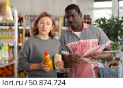 African husband and his wife are shopping in grocery store, looking for something in shop window. Стоковое фото, фотограф Яков Филимонов / Фотобанк Лори
