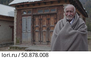 Aged local wearing traditional attire posing near weathered wooden dwelling in isolated mountain settlement, embodying rural heritage. Стоковое AI-видео, аниматор Данил Руденко / Фотобанк Лори