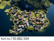 Breathtaking aerial view of a charming peninsula village surrounded by tranquil lake. Стоковое AI-изображение, AI-художник Иван Рябоконь / Фотобанк Лори