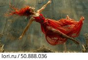 A captivating artistic image of a woman in a red translucent dress, suspended in the air while flying or dancing. Her fiery red hair flutters, creating a sense of freedom and passion. The scene is filled with movement, drama and grace. Perfect for themes of art, fashion, dance, freedom of expression and feminine power. Стоковое AI-изображение, AI-художник Анна Кривицкая / Фотобанк Лори