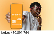 Engaging man promotes chatbot service with smartphone against a bright background. Стоковое фото, фотограф Сергей Толмачёв / Фотобанк Лори