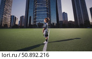 Young soccer player standing on synthetic grass field, urban skyline backdrop, sunset lighting highlighting athletic pose and ambitious spirit. Стоковое AI-видео, аниматор Данил Руденко / Фотобанк Лори