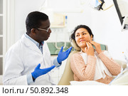 Upset Asian woman complaining to dentist about toothache. Стоковое фото, фотограф Яков Филимонов / Фотобанк Лори