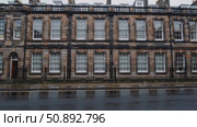 Rainwater glistening on cobblestone street, historic Georgian architecture in Edinburgh, dark stone walls framing white windows under overcast skies. Стоковое AI-видео, аниматор Данил Руденко / Фотобанк Лори