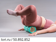 Fat woman in sportswear use myofascial release massage mfr roll on gray background, pelvic floor muscle exercise. Стоковое фото, фотограф Станислав Тарко / Фотобанк Лори