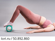 Fat woman in sportswear use myofascial release massage mfr roll on gray background, pelvic floor muscle exercise. Стоковое фото, фотограф Станислав Тарко / Фотобанк Лори