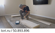 Man Professional carpenter painting wooden boards with white paint using roller brush in modern interior room during home renovation construction. Painting of wooden shelving. furniture assembly. Стоковое видео, видеограф Сергей Тимофеев / Фотобанк Лори