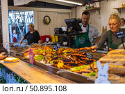 A vibrant food market scene featuring multiple chefs serving freshly cooked traditional dishes. Редакционное фото, фотограф Виктор Ветошкин / Фотобанк Лори