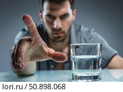 Man rejecting glass of water reaching out hand in refusal. Стоковое AI-изображение, AI-художник Иван Рябоконь / Фотобанк Лори