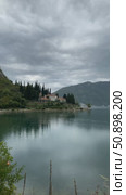 Scenic lake view with a hillside villa, surrounded by trees and reflecting water under cloudy skies. Стоковое видео, видеограф Анастасия Золотницкая / Фотобанк Лори