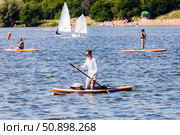 Young woman is kneeling on a sapboard and rowing with an oar. Редакционное фото, фотограф Константин Григорьев / Фотобанк Лори